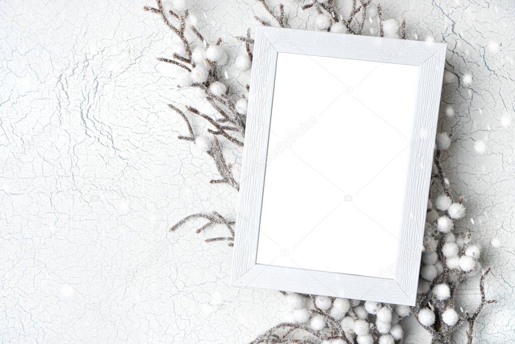 Winter mockup with empty white frame lying on the frozen branch of tree in a snow. Background with copy space. 