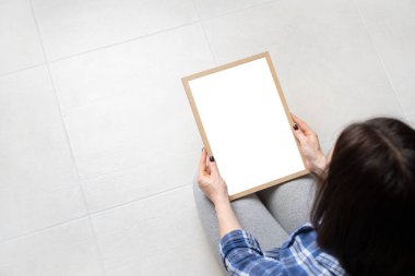 Yerde oturan ve elinde boş bir çerçeve tutan bir kız. Kopyalama alanı olan arkaplan.