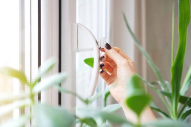 Pencere kolu kilitlenmiş, anahtar kadının ellerindeymiş. Bebek koruması için ev güvenliği kilidi. Pencere kısıtlayıcı arkaplanı.