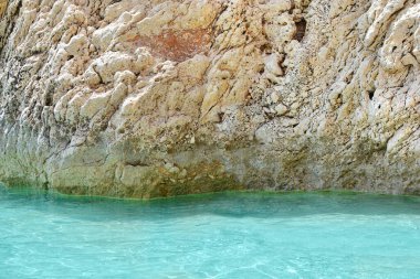 Turkuaz deniz ve dokulu kaya duvarlı bir arka plan