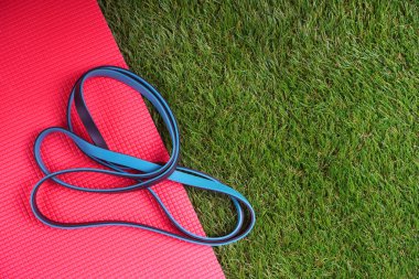 Yeşil suni çimlerin üzerinde duran dayanıklılık bandı ve spor paspası.