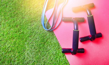 Direnç bandı, fitness paspası ve parmaklıklar yapay çimlerin üzerinde. Boşluğu kopyala.