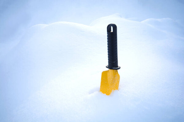 Bank of snow. Little yellow garden shovel standing in a snow