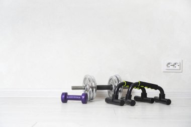 Ev konseptinde egzersiz. Salon zemininde duran dambıllar ve parmaklıklar. Kopyalama alanı olan arkaplan.  