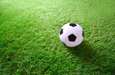 Suni çim paspasının üzerinde küçük bir futbol topu.