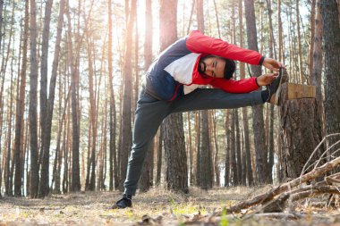 Temiz hava üzerinde esneme egzersizi. Atletik adam ormanda gerinerek ne yapıyor?.