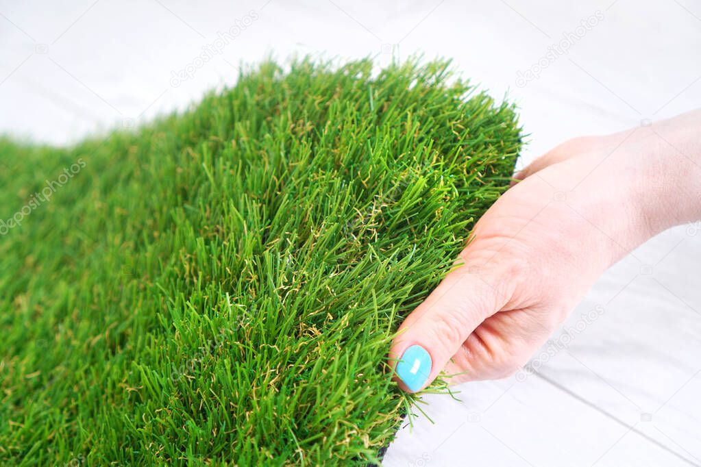 Female hand testing a green artificial grass