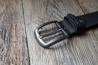 Ahşap arka planda siyah erkek deri kemer..