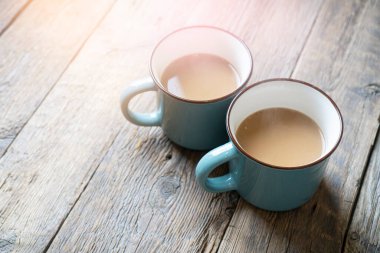 Kırsal ahşap bir masada sütlü kahve standı olan iki fincan kahve. Sabah atmosferi.