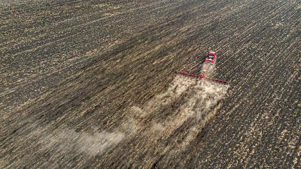 Aerial. Harvester plows the land in the field. Black earth soil cultivation. Top view from drone.