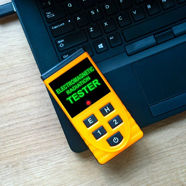 İş yerindeki ya da evdeki elektromanyetik radyasyonun ölçümü. İşyeriniz güvenli mi? Elektromanyetik radyasyon test cihazı defterde yatıyor. Kare bileşimi.