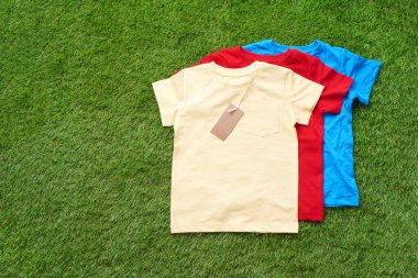 Çocuk tişörtleri suni çimenlerin üzerinde.