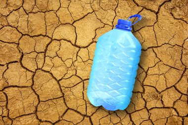 Kuru ve çatlamış toprakta bir şişe taze buzlu su. Su olmayan ülkelerde insani yardım.