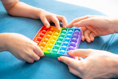 Anne ve çocuk sinir sistemini rahatlatmak için pop it baloncuk oyuncağıyla oynuyorlar..