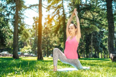 Profesyonel yoga eğitmeni şehir parkının çayırında yoga yapıyor..