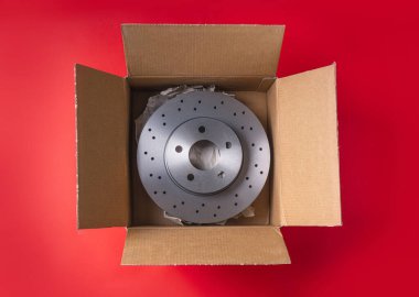 Yeni araba parçaları. Kırmızı arka planda yeni havalandırmalı fren diskleri olan bir kutu. Genel Görünüm.