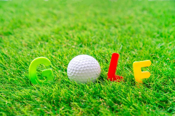 テキストゴルフボールと緑の人工芝の上に横たわるおもちゃの手紙で書かれたゴルフ — ストック写真