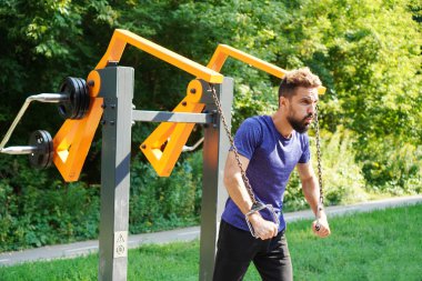 Spor salonu aç. Dışarıdaki eğitim makinesini iten adam. Belediye spor ekipmanları üzerine sokak eğitimi.