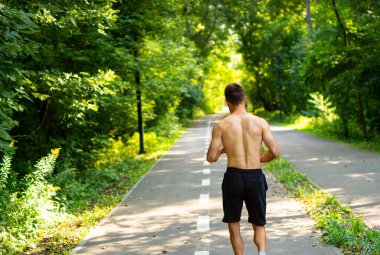 Sabah koşusu, şehir parkında koşmak. Atletik adam pistte koşuyor..