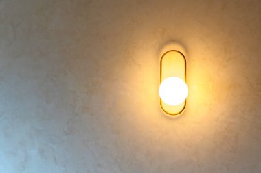 Decorative wall lamp with warm light in modern interior, creating cozy atmosphere, stylish design and contemporary home decoration.