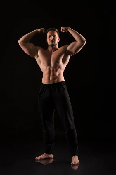 強い運動能力を持つ男は裸の筋肉体を示す 暗い背景でのスタジオ撮影 — ストック写真