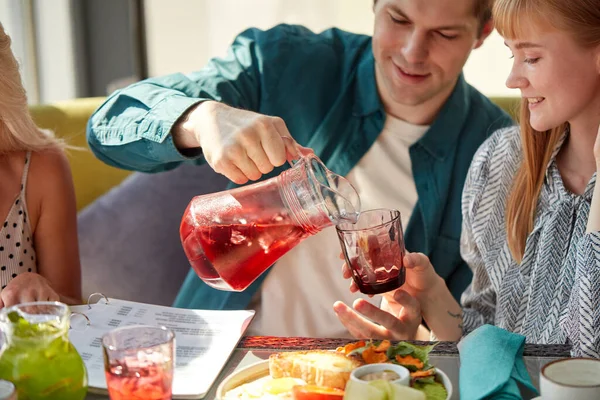 Macho está vertiendo bebida dulce en vasos para mujer — Foto de Stock