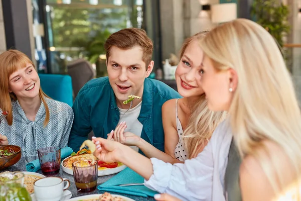 Feliz joven caucásico amigos reuniéndose en la cafetería, sentado a la mesa, charlando, hablando — Foto de Stock