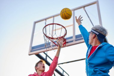 Genç basketbolcular uçuyor ve sayı yapıyorlar.