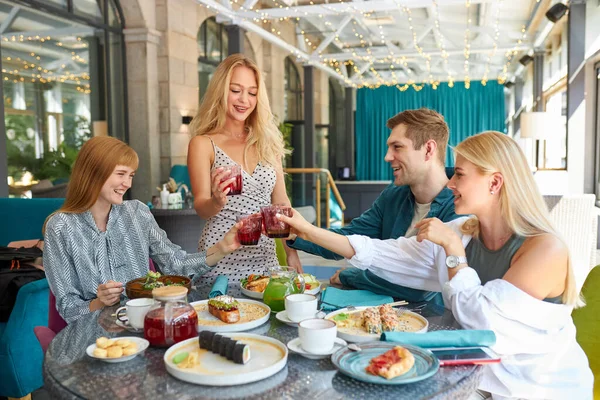 Gruppe junger Freunde klirrt mit Gläsern im Café — Stockfoto