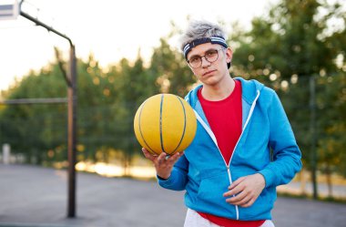 Elinde basketbol topu olan beyaz bir çocuğun portresi.