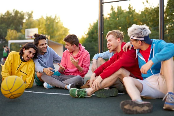 Jonge vrienden zitten op basketbalveld, ontspannen en pauze na wedstrijd — Stockfoto