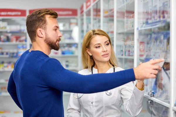 Άνδρας πελάτης έχει μια διακριτική συζήτηση με φαρμακοποιό στην φαρμακευτική — Φωτογραφία Αρχείου