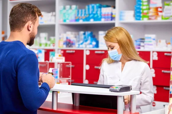 male customer having a discrete talk with druggist in pharmacy