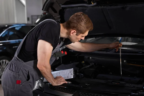 Reparatie in actie. hardwerkende man werknemer in uniform werkt in de auto salon — Stockfoto