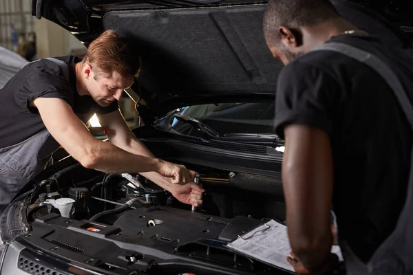 Multi-etnische team van Afrikaanse en Kaukasische mannen die werken in de auto-service — Stockfoto