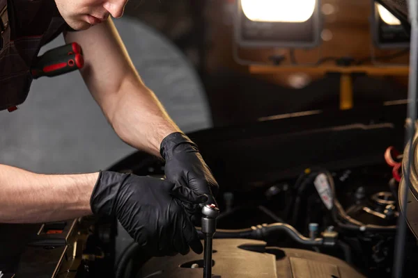 Auto mecânico masculino torce o elemento ausente dentro do carro usando chave — Fotografia de Stock