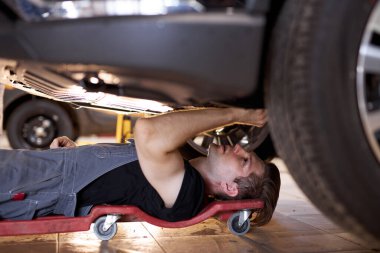 Zeminde tek başına çalışan konsantre otomobil tamircisine yan bakış