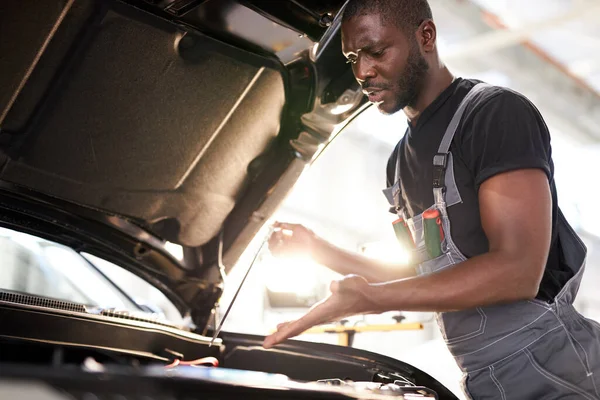 Reparatie in actie. hardwerkende man werknemer in uniform werkt in de auto salon — Stockfoto