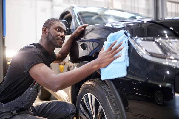 Afro americano meccanico auto uomo pulisce la superficie della macchina dopo la lucidatura — Foto Stock