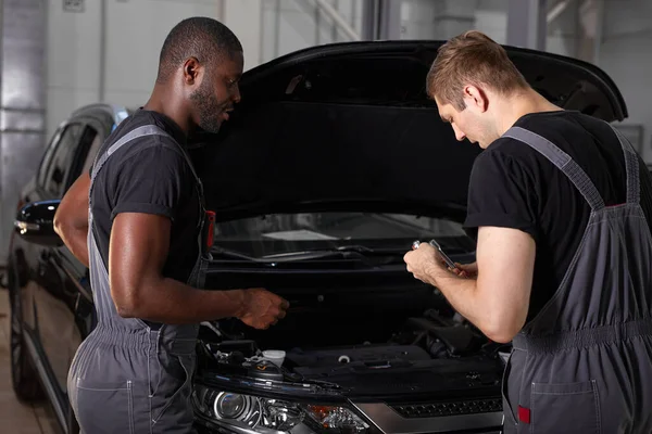 Equipe multi-étnica de homens africanos e caucasianos que trabalham no serviço de automóveis — Fotografia de Stock