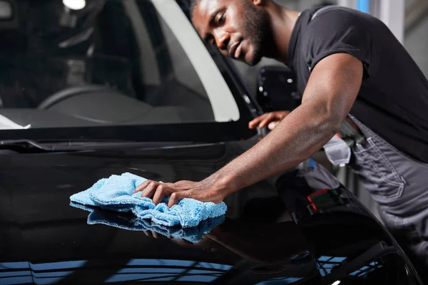 Negro trabajador mecánico auto limpieza superficie del coche — Foto de Stock