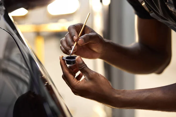 Joven afro auto servicio trabajador está pintando detalles del coche — Foto de Stock