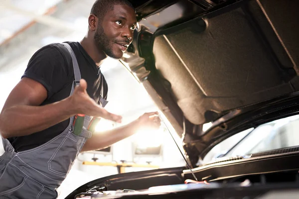 Zwart-Afrikaanse automonteur begrijpt niet hoe de machine op te lossen — Stockfoto