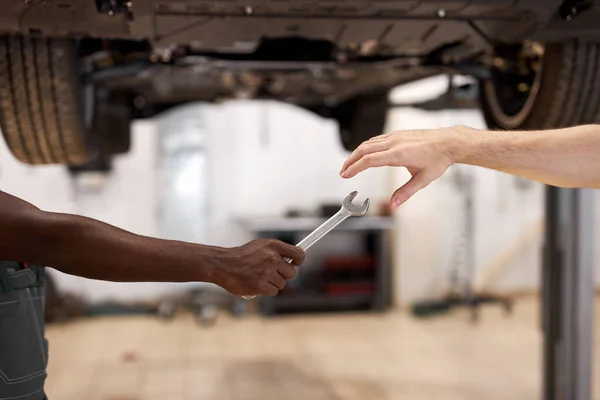 Two auto mechnic colleagues giving instrument tools to each other — Stock Photo, Image