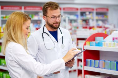 Eczanede kendinden emin erkek ve kadın eczacılar konuşuyor.