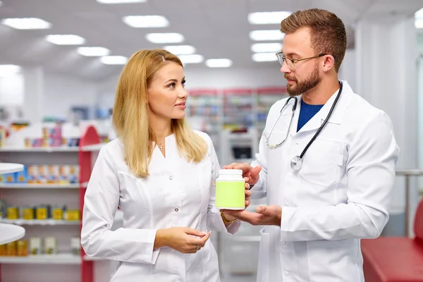 Zwei professionelle Apothekerkollegen bei der Erfüllung eines Rezeptes mit Medikamenten in der Hand — Stockfoto