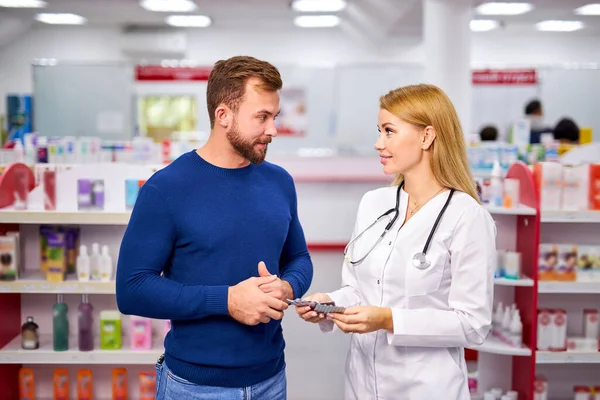 Profesjonalna aptekarka pomaga klientowi w wyborze leków na receptę — Zdjęcie stockowe