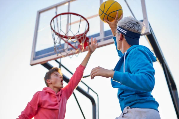 Adolescentes canasta de tiro y jugar al baloncesto, vista inferior gran angular — Foto de Stock