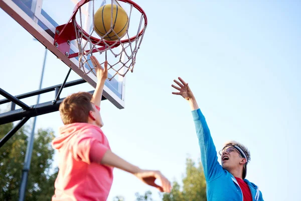 Adolescentes canasta de tiro y jugar al baloncesto, vista inferior gran angular — Foto de Stock