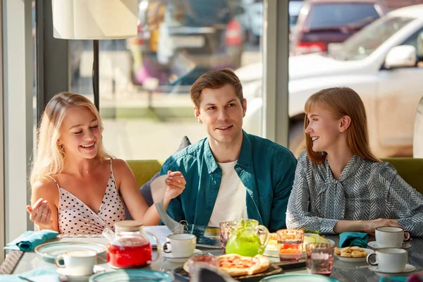 Три колеги в кафе обговорюють їжу в меню — стокове фото